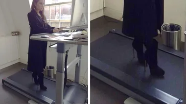 A woman using a treadmill desk while wearing high heels in an office setting.