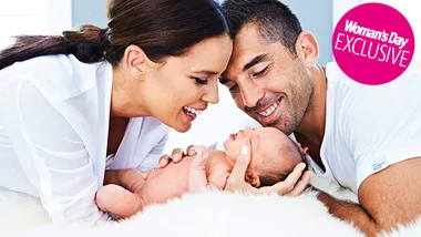 Couple joyfully gazes at their newborn baby, smiling and embracing.