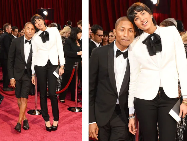 Two people posing on the red carpet; one in a tuxedo with shorts, the other in a white jacket and black pants.