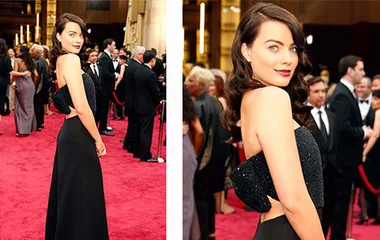 Woman in an elegant black gown on the red carpet, surrounded by other formally dressed attendees.