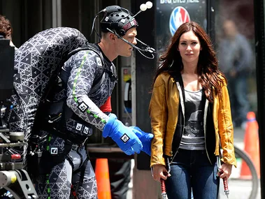 Behind-the-scenes of "Teenage Mutant Ninja Turtles" with an actress in yellow jacket, actor in motion-capture suit.