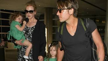 Family walking through an airport, with two children in matching green dresses.