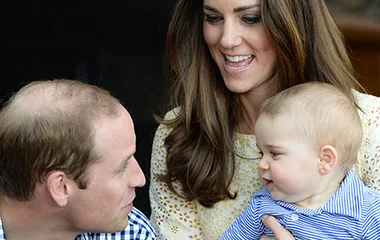 A smiling couple with a baby in their arms, all enjoying a moment together.