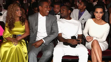 Beyoncé, Jay-Z, Kanye West, and Kim Kardashian sit together at a formal event, engaged in conversation.