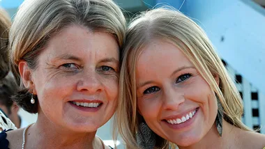 Two women smiling together against a blurred backdrop, symbolizing a close mother-daughter relationship.