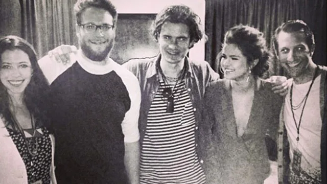 Group of five people, including a woman in profile smiling, posing indoors in a casual setting.