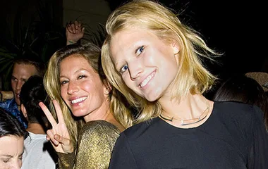 Two smiling women at a party, one making a peace sign.