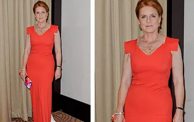 A woman in a form-fitting red dress stands indoors, holding a colorful clutch bag, with light brown hair styled neatly.