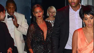 Group of people dressed formally, walking together at an event; elegantly dressed individuals in focus.