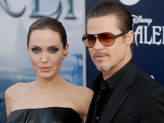 Two people posing on a red carpet, one wearing sunglasses.