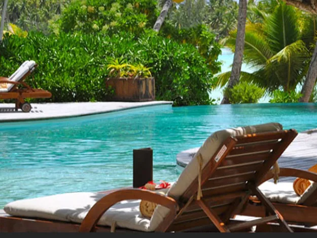 Sun loungers by a tropical pool with lush greenery in the background.