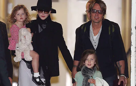 Nicole Kidman and Keith Urban arriving at Sydney airport with their two daughters, both holding stuffed toys.