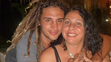 A young man with dreadlocks embraces a smiling woman in an outdoor setting at night.