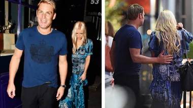 Two people in blue attire walking and talking closely on a street, one with blonde hair and floral dress.
