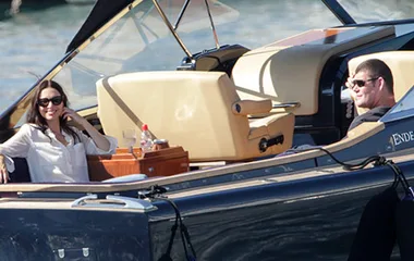 A man and woman relax on a luxury boat, smiling and enjoying the sunny weather.