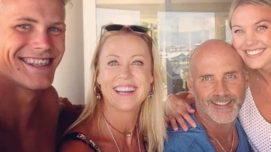 Four smiling people taking a selfie together indoors with a view of the outside in the background.