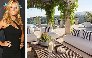 Heidi Klum in black dress beside luxurious terrace with white sofas and scenic view.