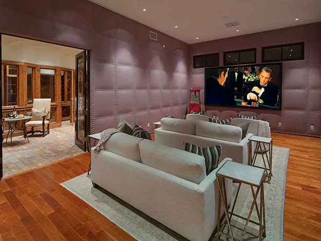 Home theater with plush seating, wood floors, and a large screen showing a scene from a movie with poker players.