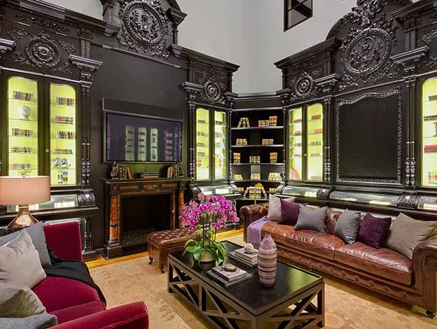 Elegant library with dark wood panels, leather sofas, ornate decor, and bookshelves lit with warm light.