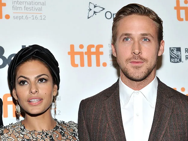 Two people posing at the Toronto International Film Festival in front of a branded backdrop.