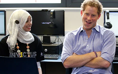 A man and a woman in a computer lab; the woman wears a hijab and an Invictus shirt, while the man smiles with arms crossed.