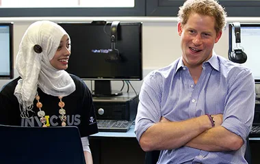 A man and a woman in a computer lab; the woman wears a hijab and an Invictus shirt, while the man smiles with arms crossed.