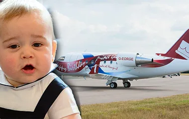 Baby in front of a private jet with "Happy Birthday" and "G-George" written on it.