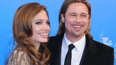 A smiling couple dressed formally at a blue-carpet event.