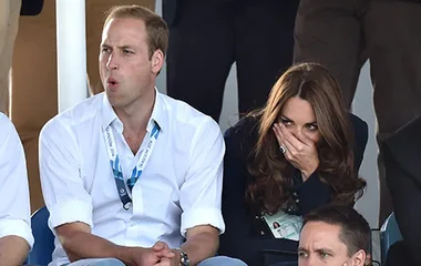 Spectators reacting with surprise and amusement at a sporting event, seated with lanyards.