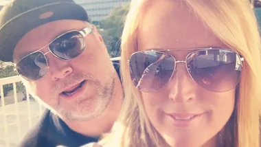 Two people wearing sunglasses outdoors, smiling.
