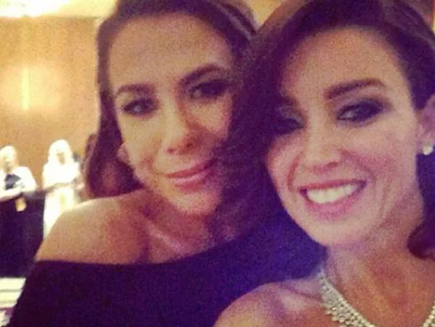 Two women smiling and taking a selfie at a formal event.