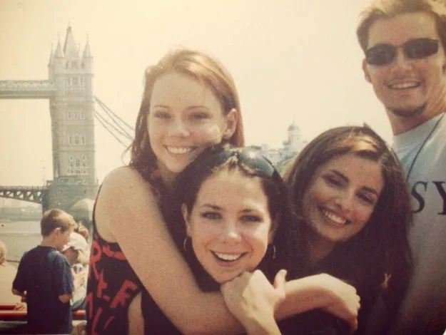 Group of four people smiling near Tower Bridge, London.