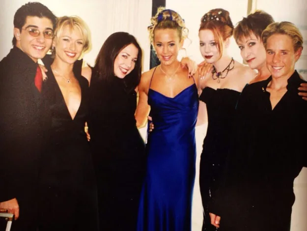 Group of seven people dressed formally, smiling at the camera.