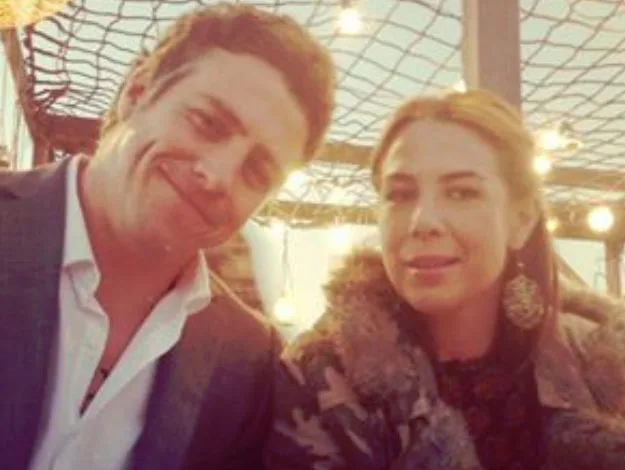 Two people seated together under warm lights, smiling at the camera.