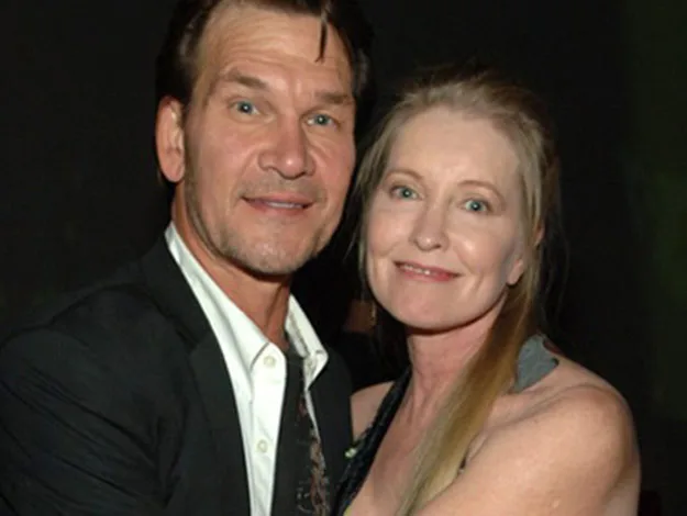 A man in a suit and a woman in a dress smiling together, embracing at an event.
