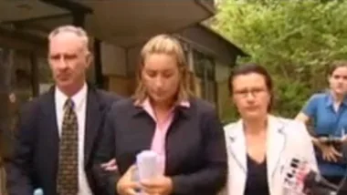 Three people walking outside a building, with one person holding papers in the center.