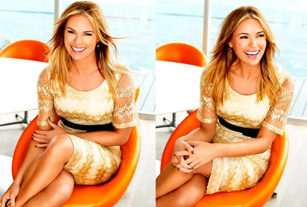Woman in a beige lace dress sitting in an orange chair, smiling brightly.