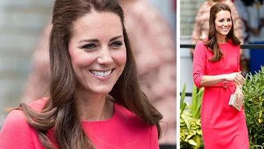 A woman in a pink dress smiles while holding a clutch, outdoors, with greenery in the background.