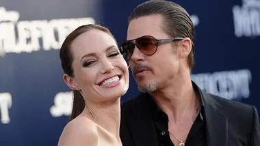 A smiling couple posing together on the red carpet at a movie premiere event.