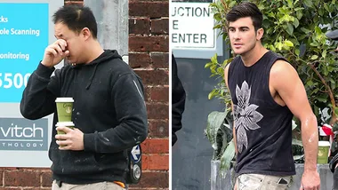 Two men in casual attire, one wearing a black hoodie holding a coffee, the other in a sleeveless shirt with paint stains.