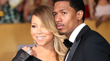Nick Cannon and woman in formal attire smiling at a public event.