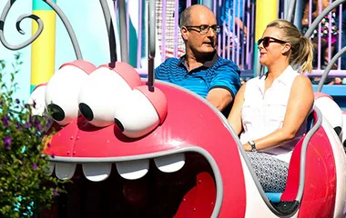 Adults enjoying a colorful ride at Universal Studios, seated in a whimsical car with large cartoon eyes.