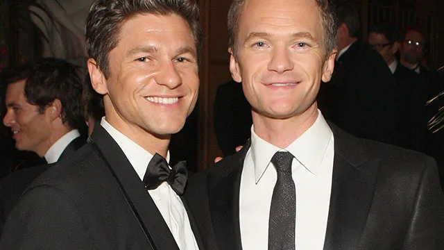 Two men in formal suits smiling at an event.