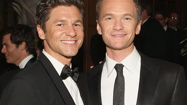 Two men in formal suits smiling at an event.
