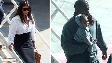 Man holding a baby in a hoodie and woman descending stairs in sunglasses, outside in a sunny setting.