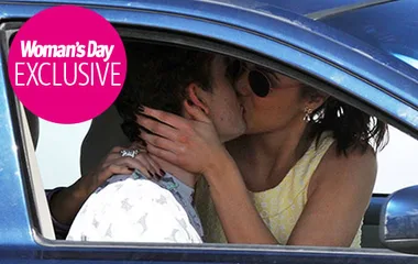 A couple sharing a kiss inside a car, with "Woman's Day Exclusive" text overlaid.