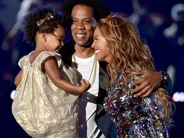 Family on stage sharing a joyful moment, hugging and smiling together under bright lights.