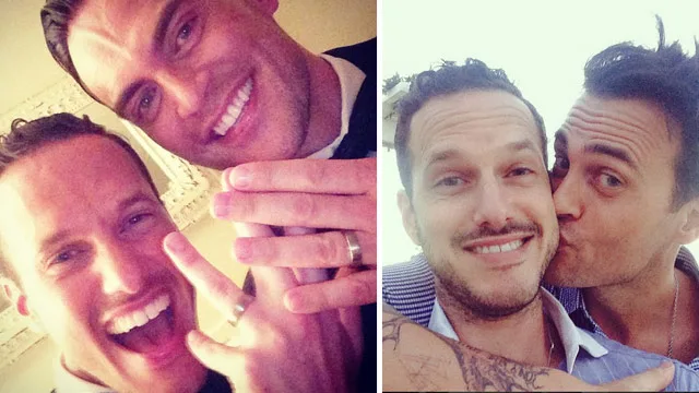 Two happy men wearing wedding rings, one kissing the other on the cheek, celebrating their marriage.