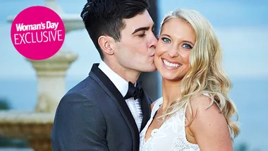 Man kisses woman on the cheek at a wedding, both smiling, outdoor setting, exclusive Woman's Day feature.