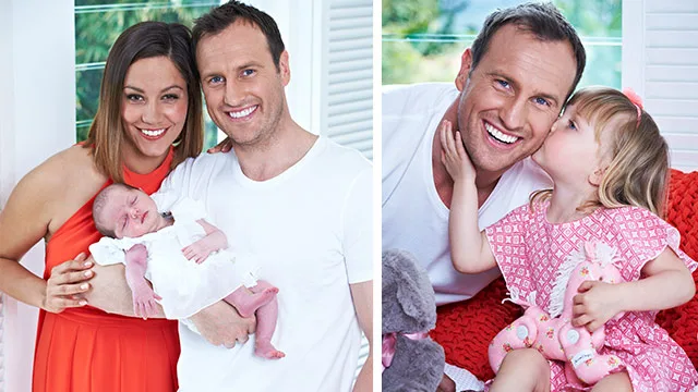 Family portrait: A smiling couple holds a newborn, and a man sits beside a young girl who kisses his cheek, surrounded by toys.